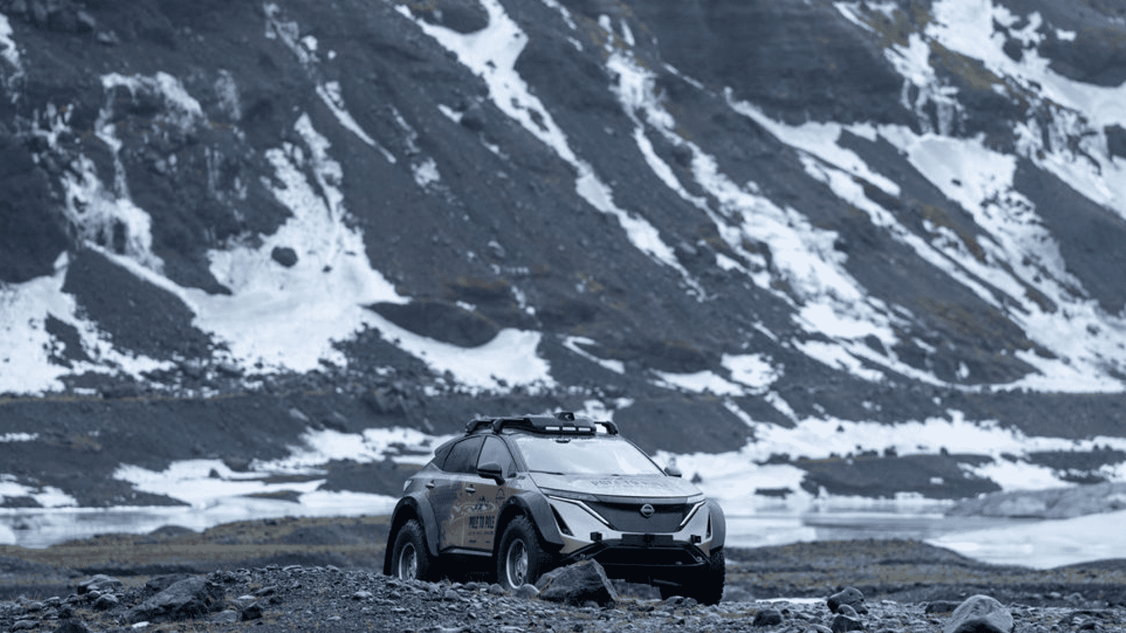 Nissan Ariya parked in front of a snowy mountain lake