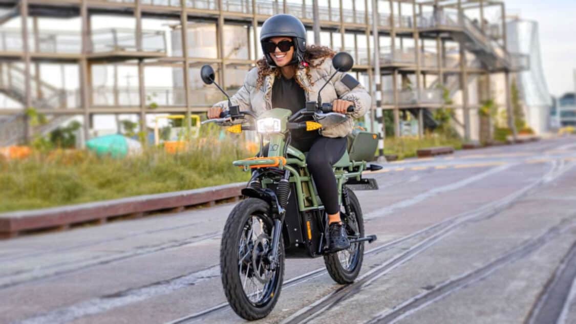 Photo of woman wearing helmet and riding UBCO off-road electric bike on non-fuctional train tracks