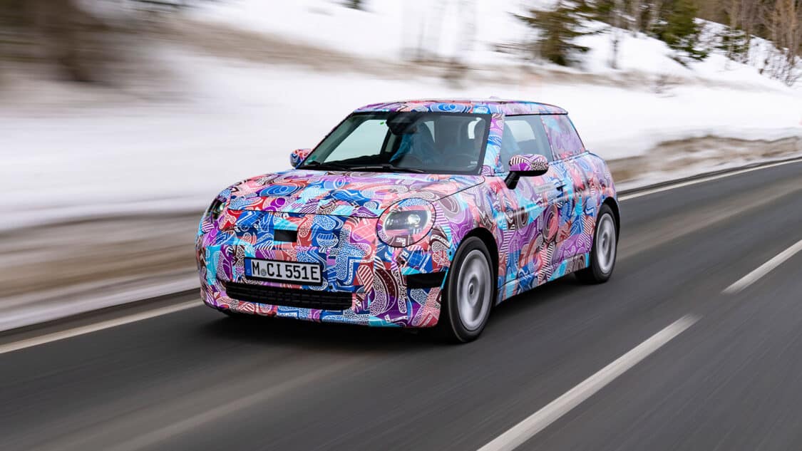 photo of electric mini cooper with multi-colored graphics vehicle wrap on street next to mountain in the winter