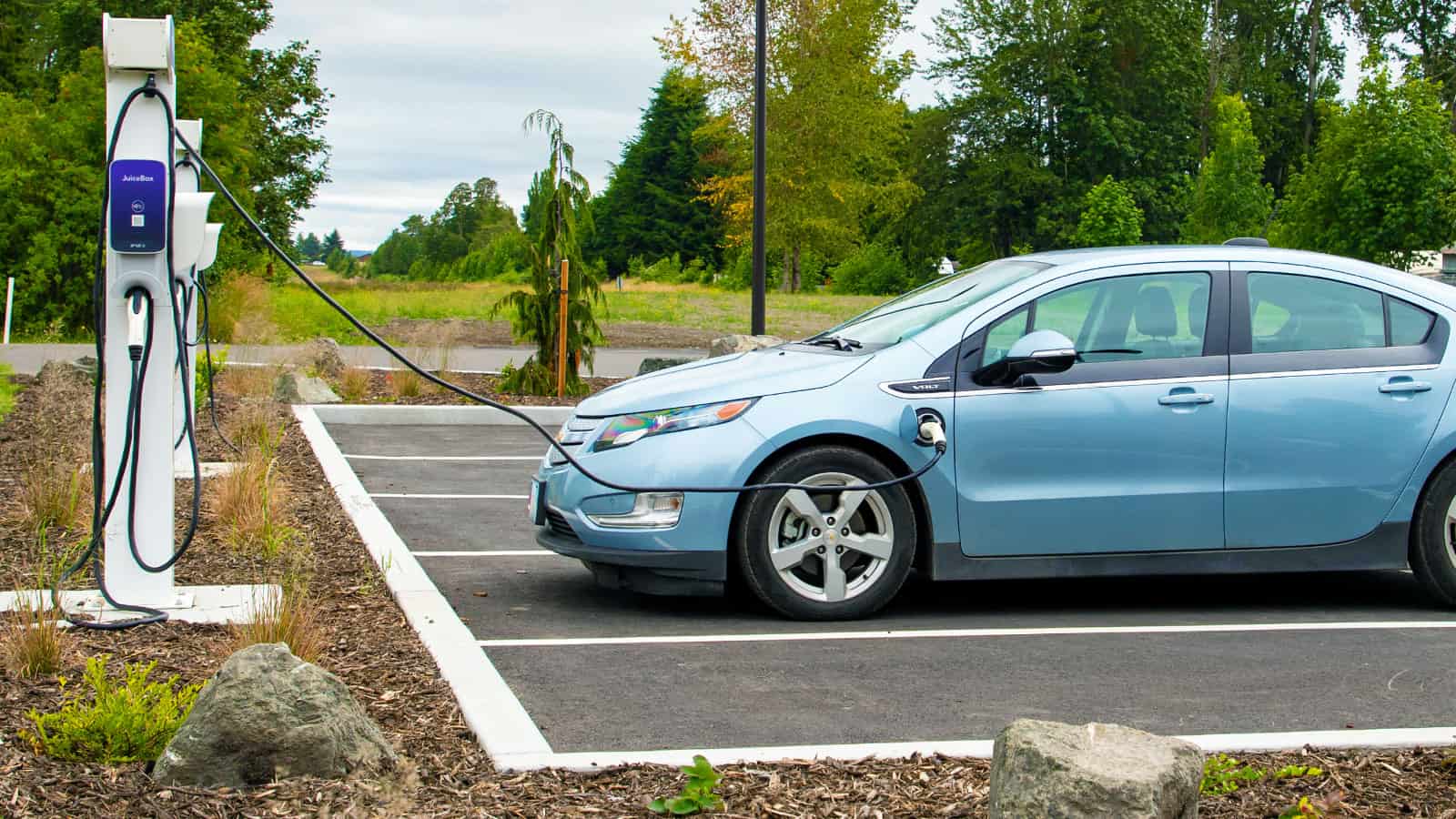 Blue Chevrolet Volt easily charging in a parking lot challenges the myth that electric vehicles are not convenient to charge
