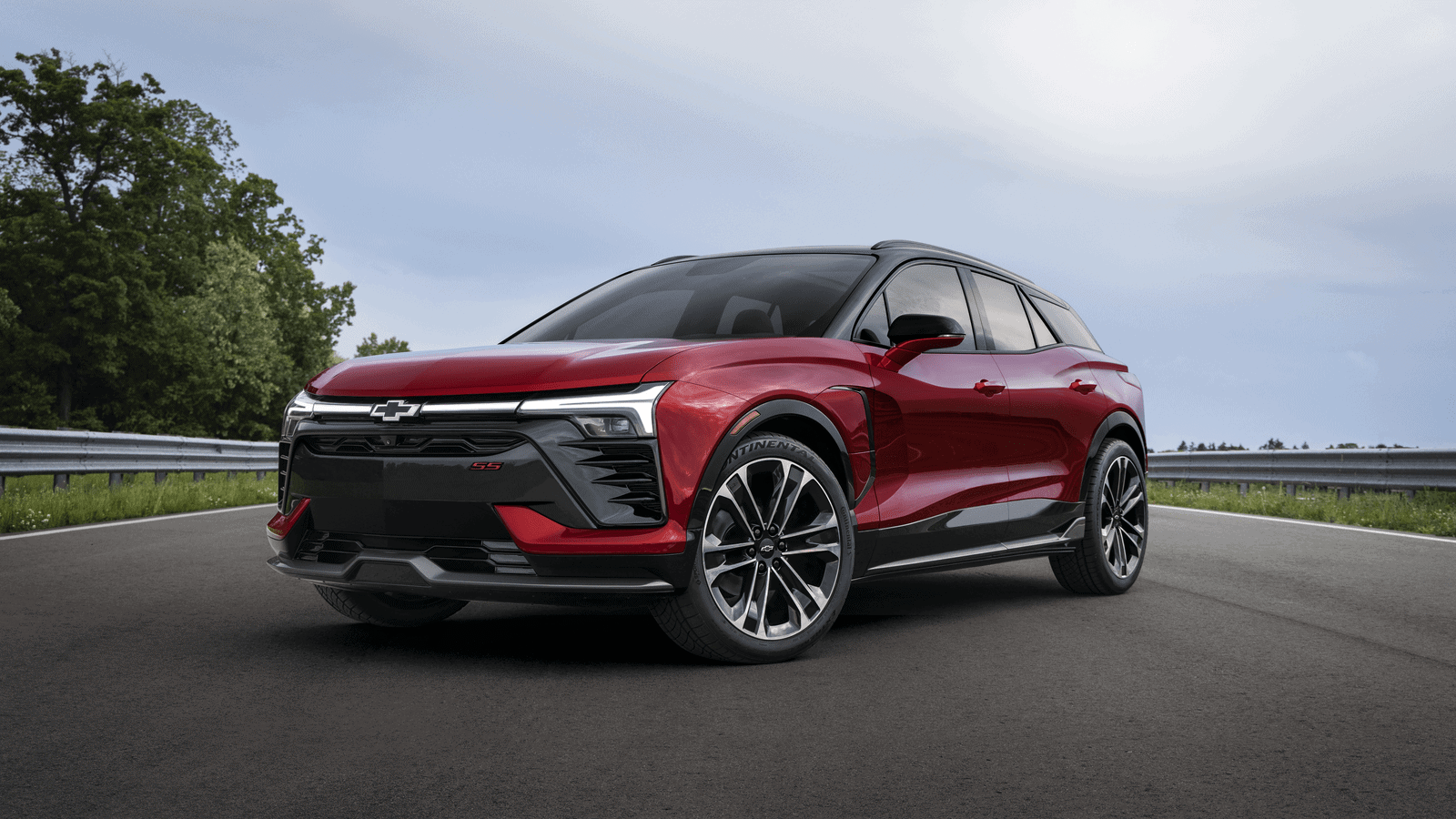 Photo of Three-quarter view of 2024 Chevrolet Blazer EV SS in Radient Red Tintcoat on a road with trees. Preproduction model shown. Actual production model may vary. 2024 Chevrolet Blazer EV available Spring 2023.