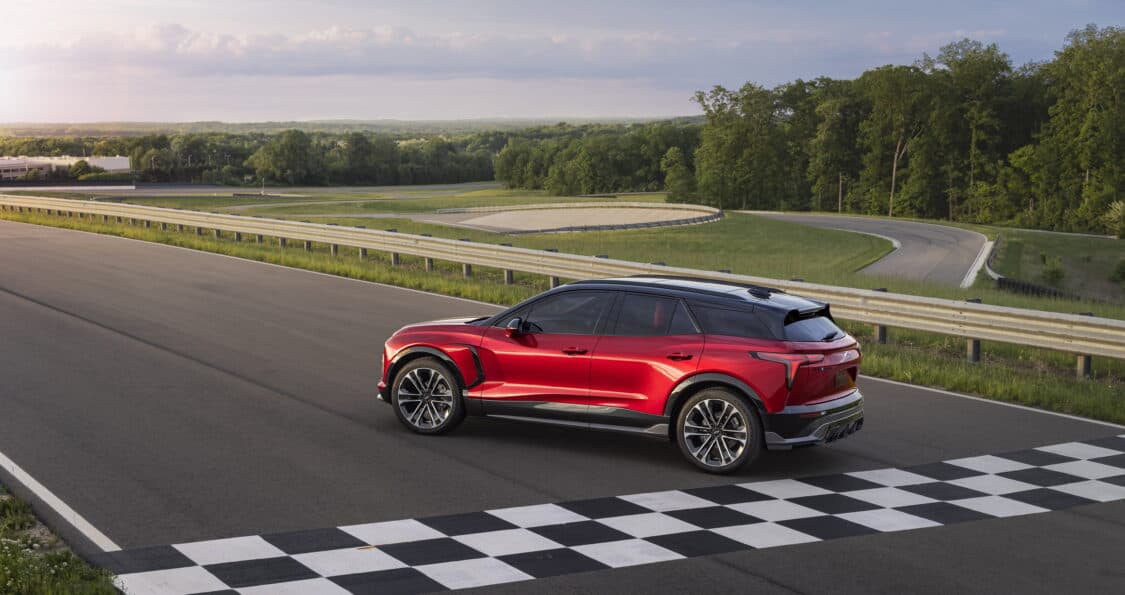 Photo of Side view of 2024 Chevrolet Blazer EV SS in Radiant Red Tintcoat crossing checkered finish line. Preproduction model shown. Actual production model may vary. 2024 Chevrolet Blazer EV available Spring 2023.
