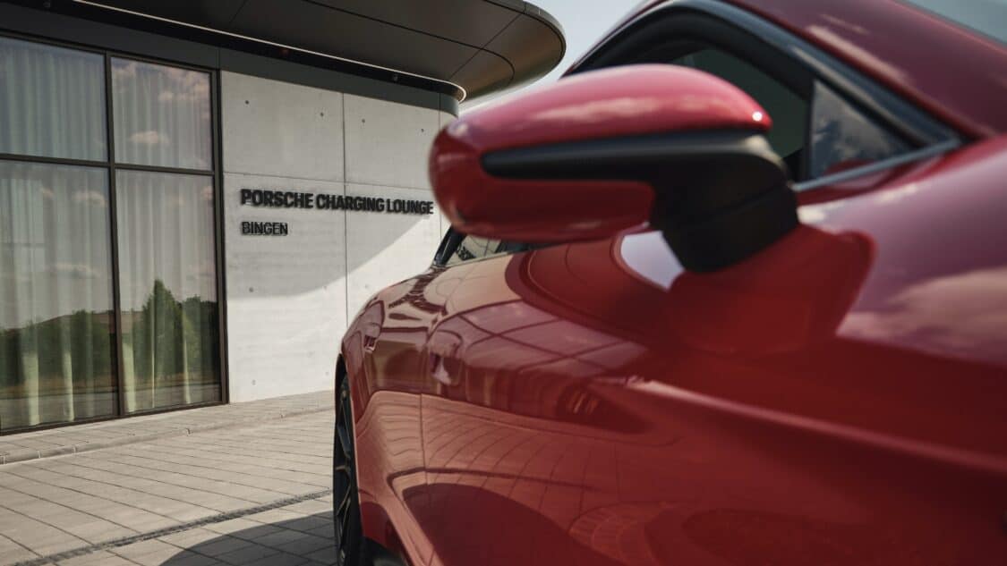 Photo of a red Porsche Taycan parked at the Porsche Charging Lounge in Bingen am Rhein, Germany.