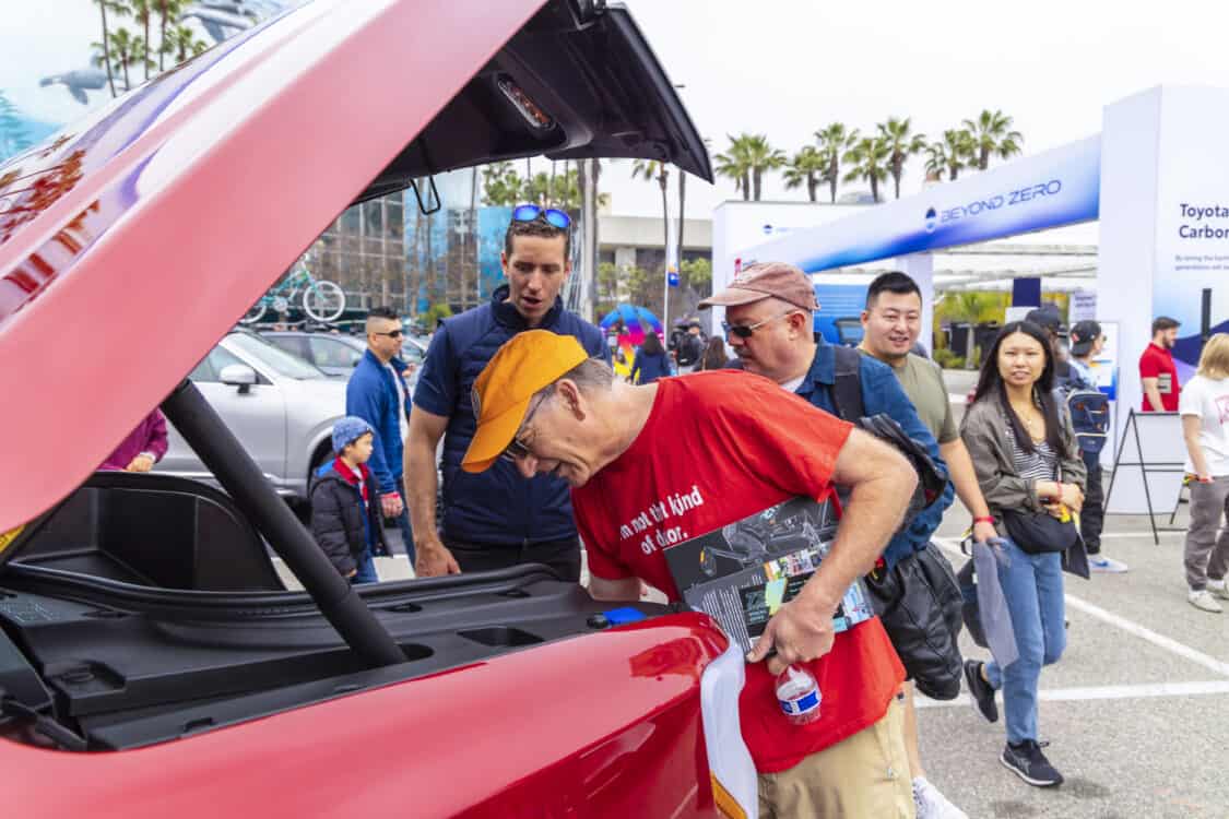 Photo of Ford booth at Electrify Expo Long Beach featuring customers looking inside frunk