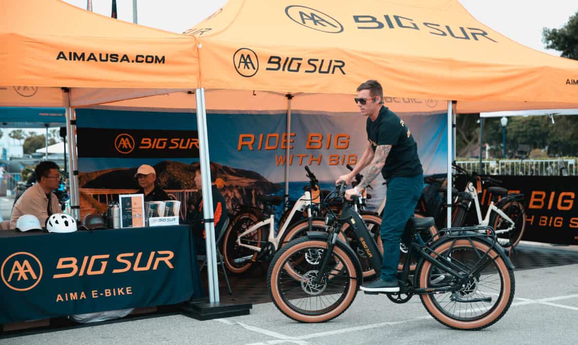 Photo of Electrify Expo attendee test riding the AIMA Big Sur matte black electric bike.