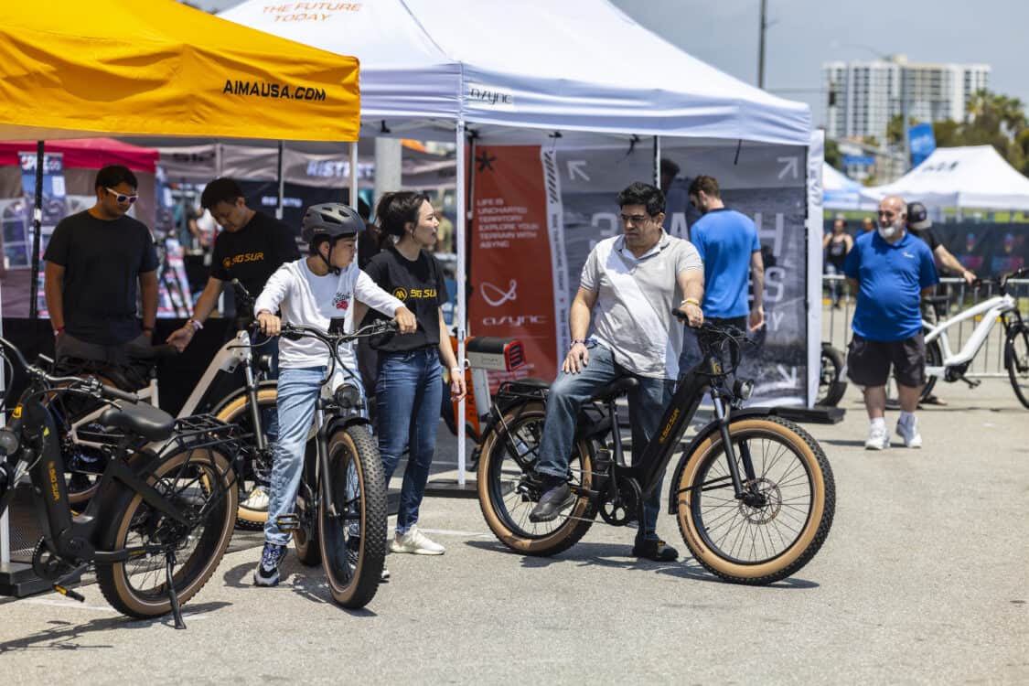Photo of Electrify Expo attendees test riding the AIMA Big Sur matte black electric bike.