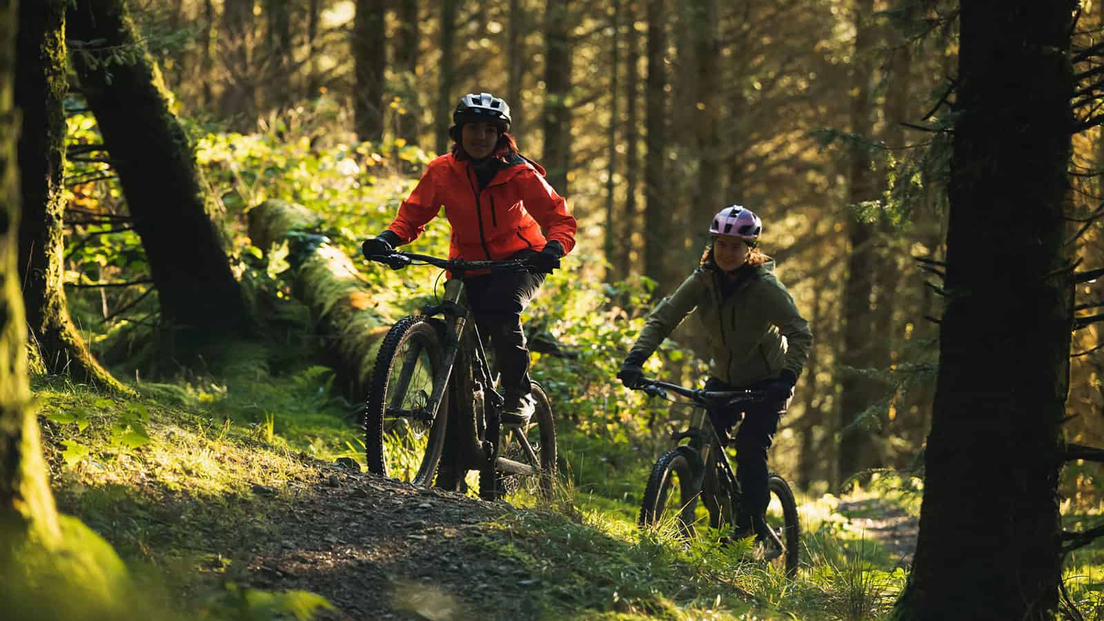 The 5 best electric mountain bikes two women riding Canyon bikes in a dense forest