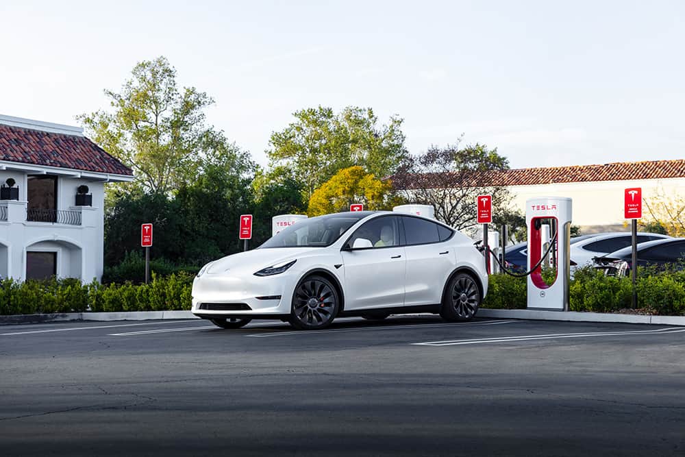 Tesla Supercharger with white car being charged, with more brands embracing NACS compatibility, it's important not to have broken EV chargers.
