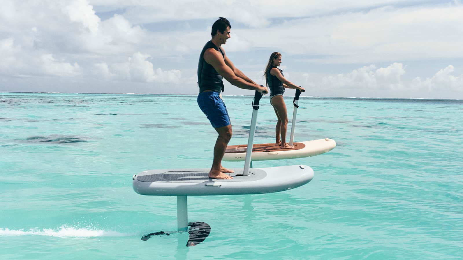 man and woman using fliteboard hydrofoil on turquoise waters