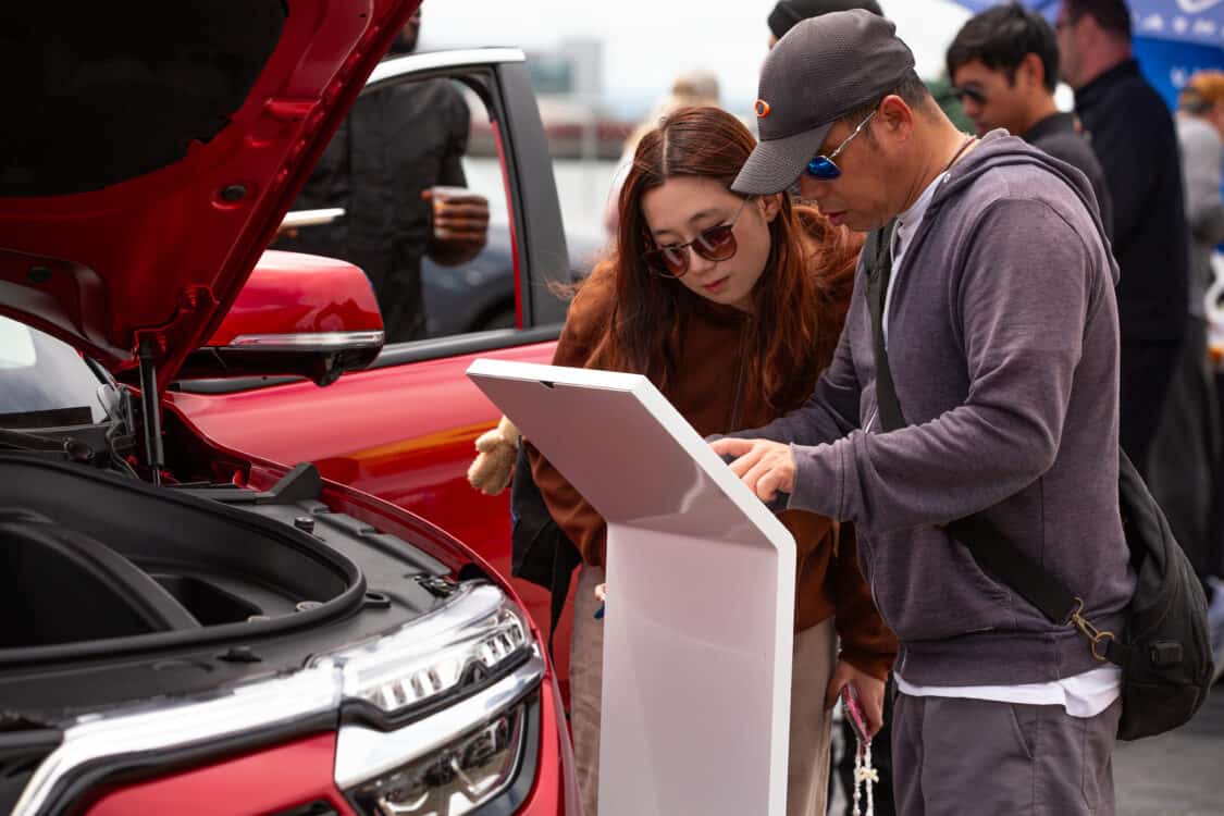 Image showcasing a man and woman looking at the features of a VinFast VF 8 in red at Electrify Expo San Francisco