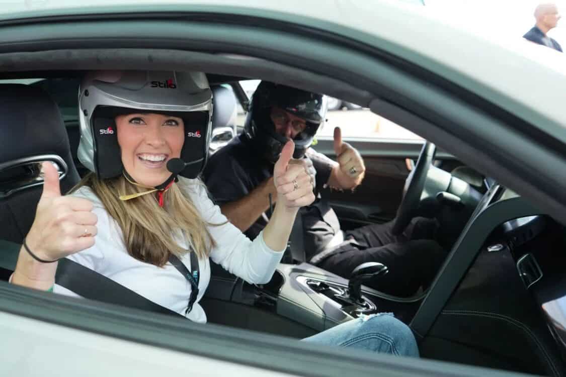 Image showcasing Miss GoElectric giving a thumbs up with a professional driver