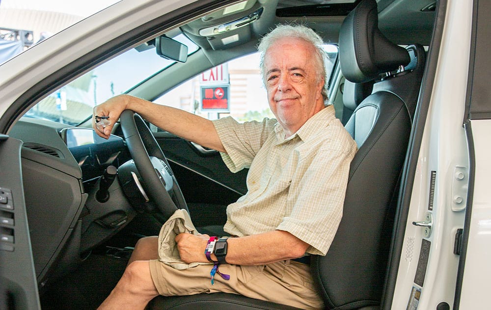 Older man sitting in the driver seat of an EV, reflecting the electric vehicle generation gap in EV adoption.