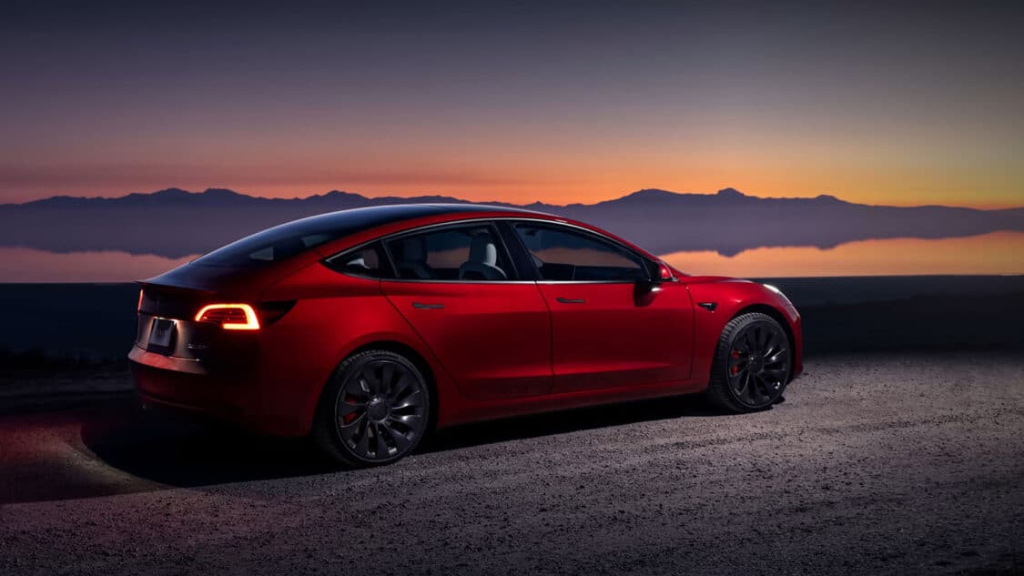 Tesla Model 3 with lake and sunset sky