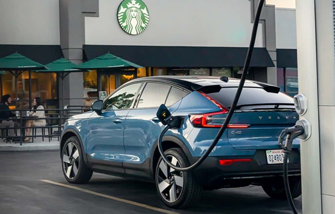 Volvo parked in front of a Starbucks charging, EV adoption 2024