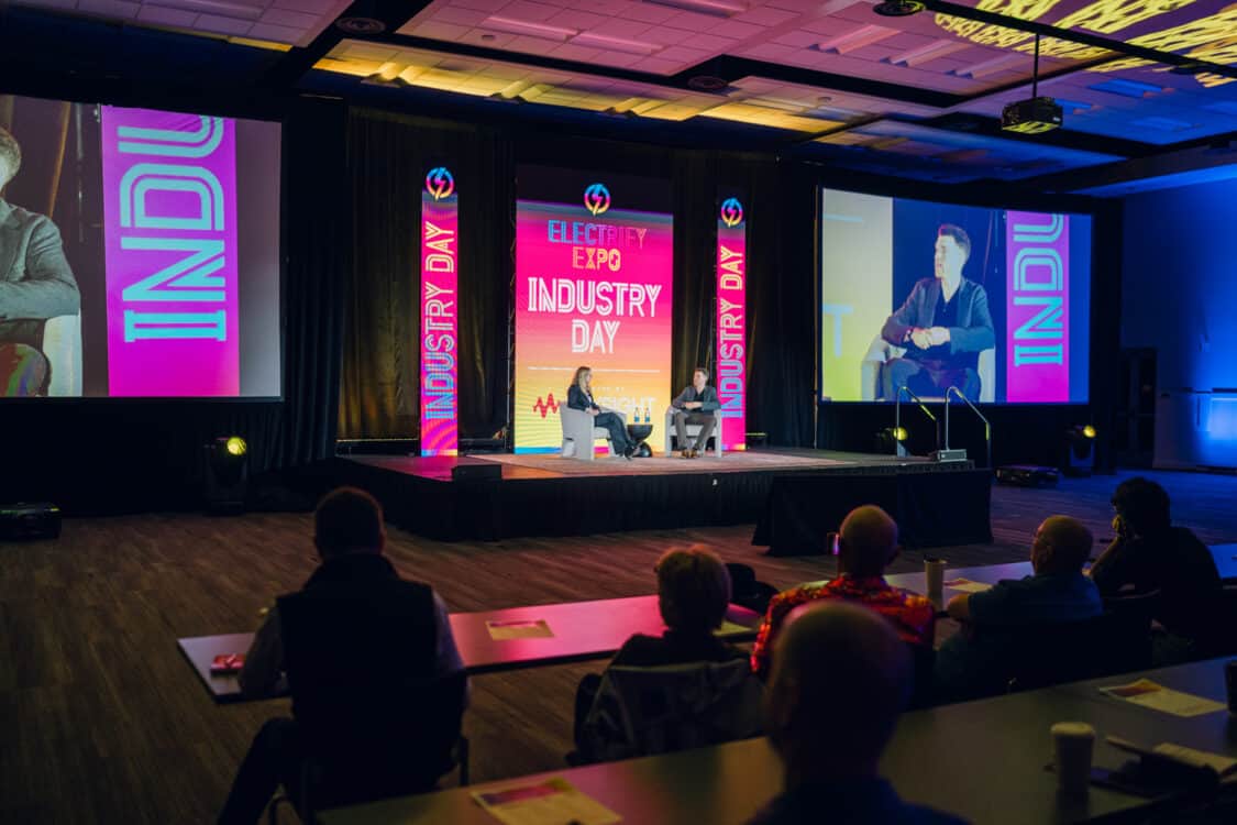 Image showcasing Marvin C. Kroger, Electric Vehicle Business Development Manager at Keysight Technologies, and Jennifer Hiller, Energy Reporter from The Wall Street Journal, engaged in a fireside chat about V2G technology at Electrify Expo Industry Day in Austin, TX 2023