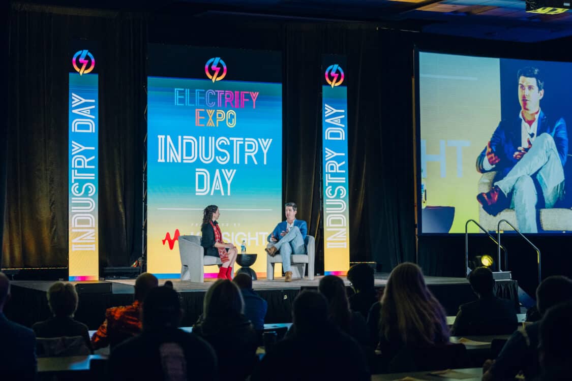 Image showcasing Sean Ackley, Head of Charging & Energy at VinFast, speaking with Automotive Journalist Kristin Shaw in a fireside chat at Electrify Expo Industry Day in Austin, TX 2023