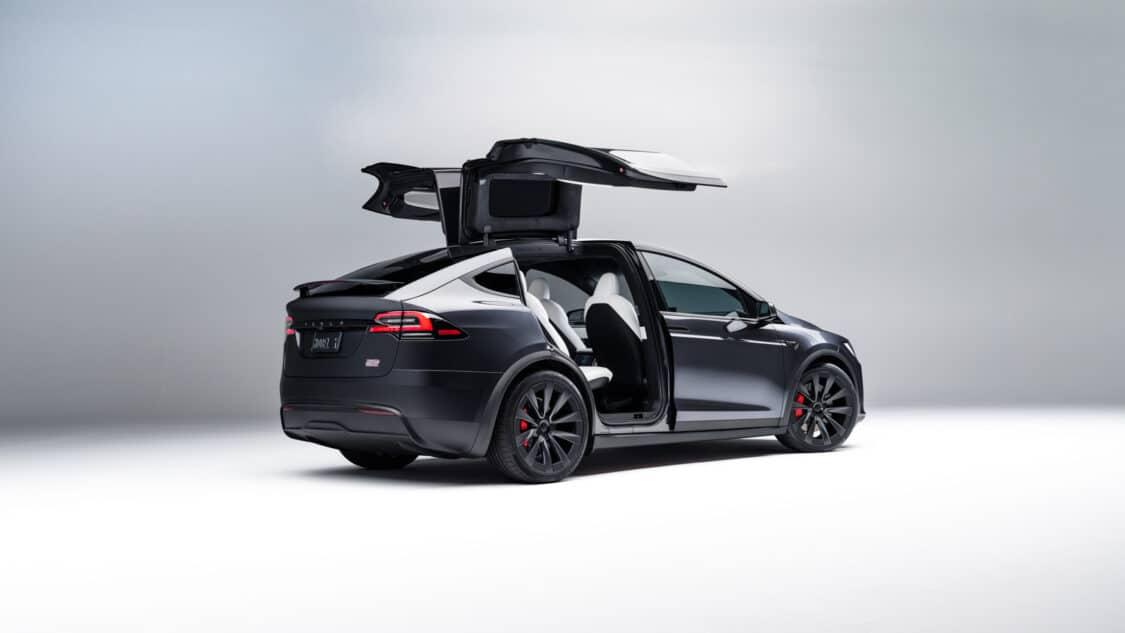Image showcasing rear of 2024 Tesla Model X in black with gull wing doors open