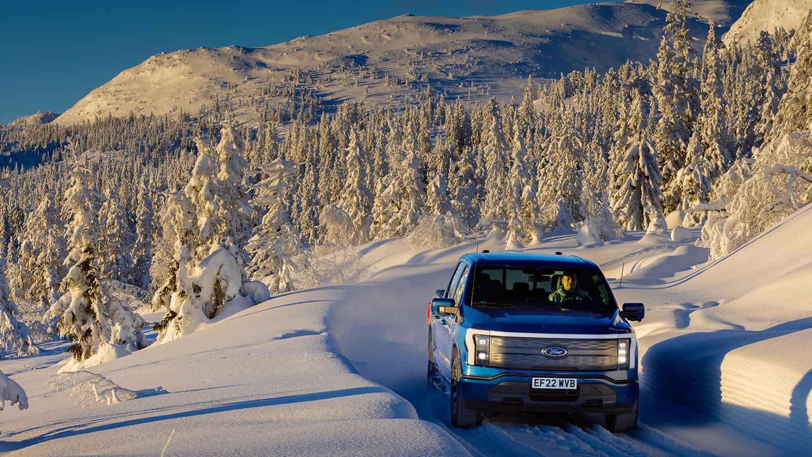 Ford F-150 Lightning driving up a snowy mountain, sales up in 2023