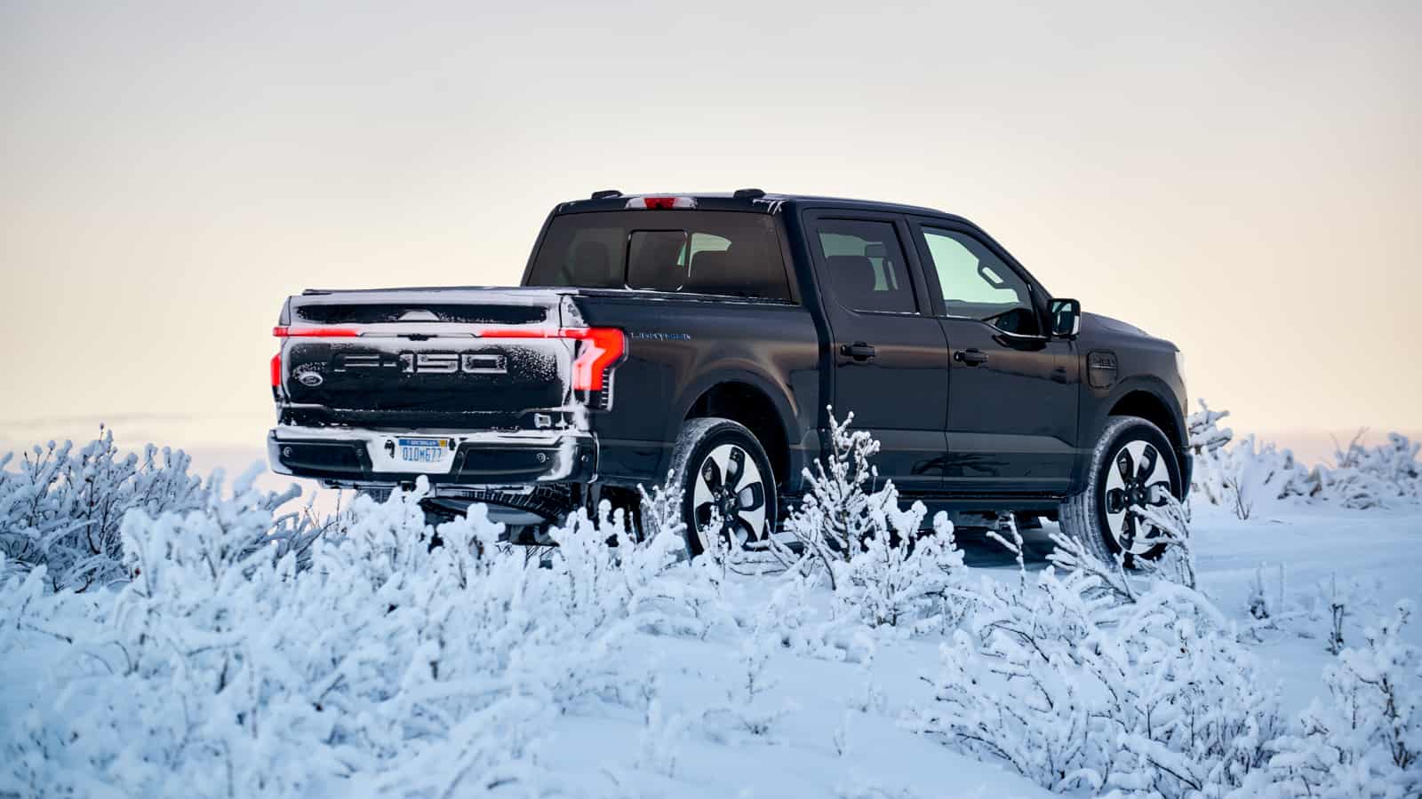 Image showcasing black 2022 Ford F-150 Lighting EV truck in snow and cold weather