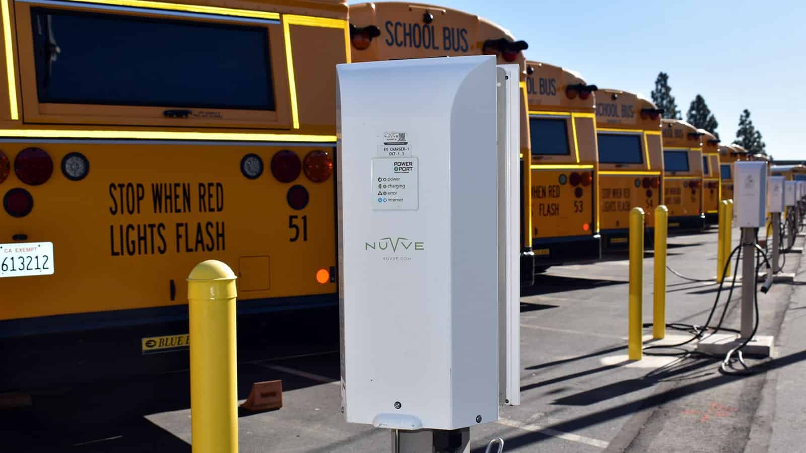 Nuvve EVSE in a row with electric school buses parked next to them ready to be charged.