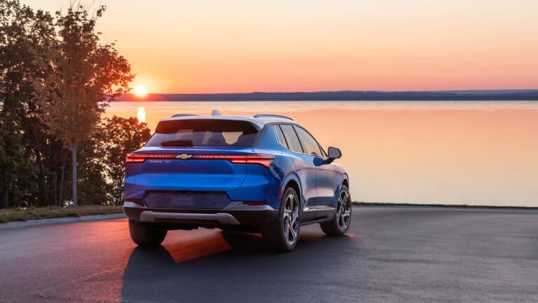 Chevrolet Equinox EV from rear view and parked and overlooking water at sunset.