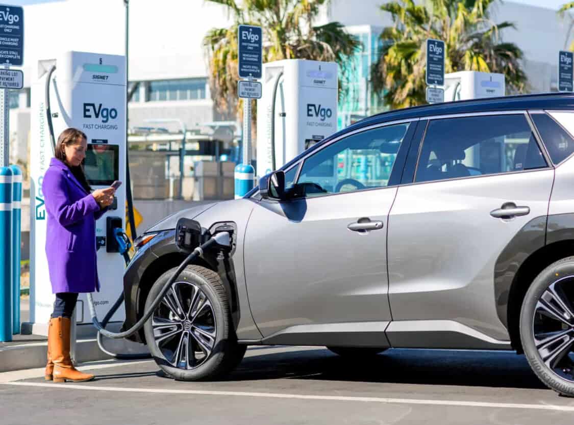 Woman charging a Toyota bZ4X electric SUV at EVgo fast charging station