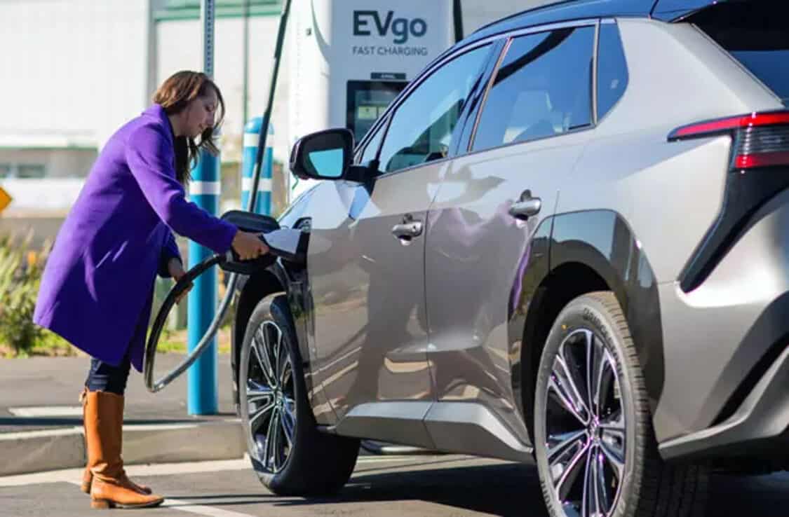 Woman charging a Toyota bZ4X electric SUV at EVgo fast charging station