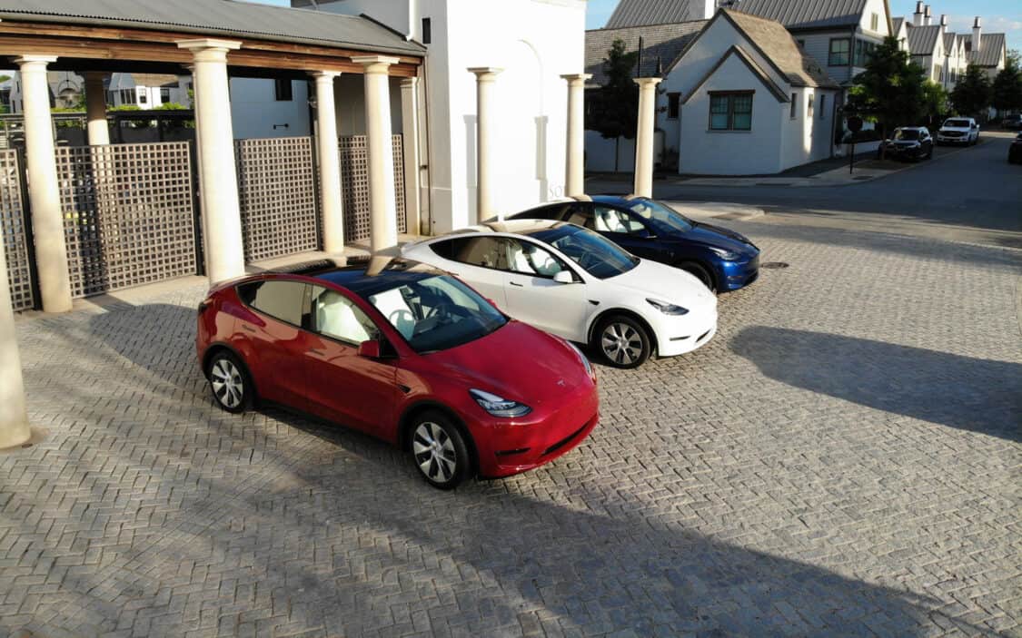 Red Tesla Model Y, White Tesla Model Y, and Blue Tesla Model Y photographed near the town square for Independence Day