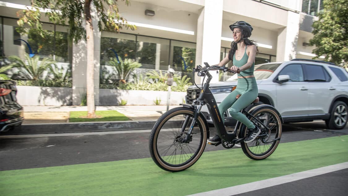 woman riding an e-bike in a bike lane, batteries can be sent for recycling.