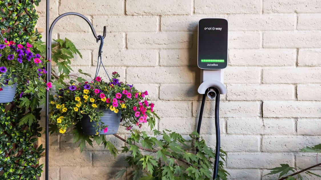 juicebox ev charger mounted to brick wall with flowers beside it.