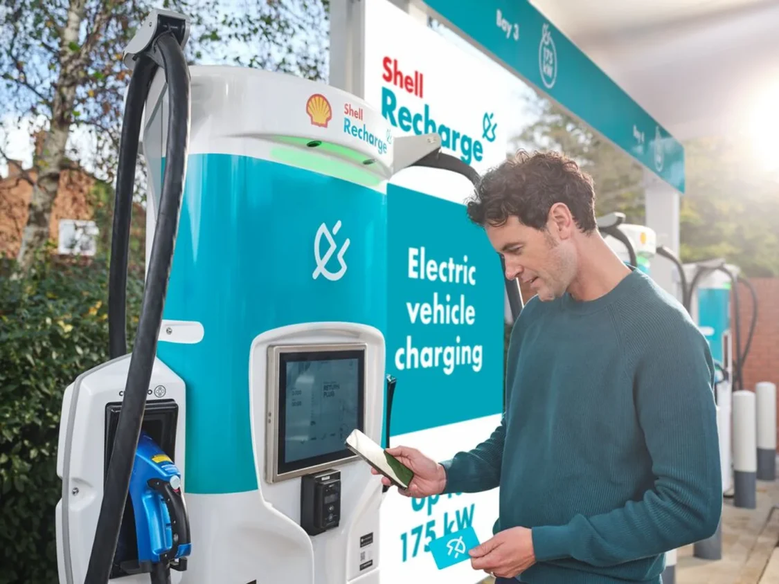 Shell big oil electric vehicle charging station with man looking at phone