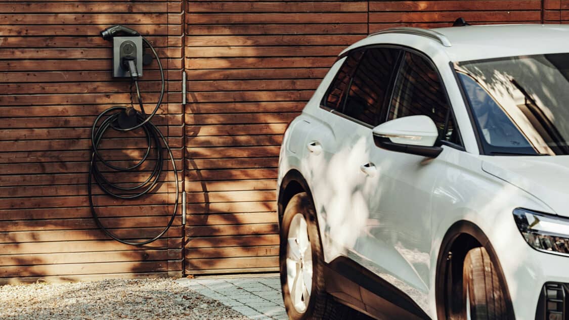 Zaptec wall charger installed on wood wall with car parked in front, can use solar for charging