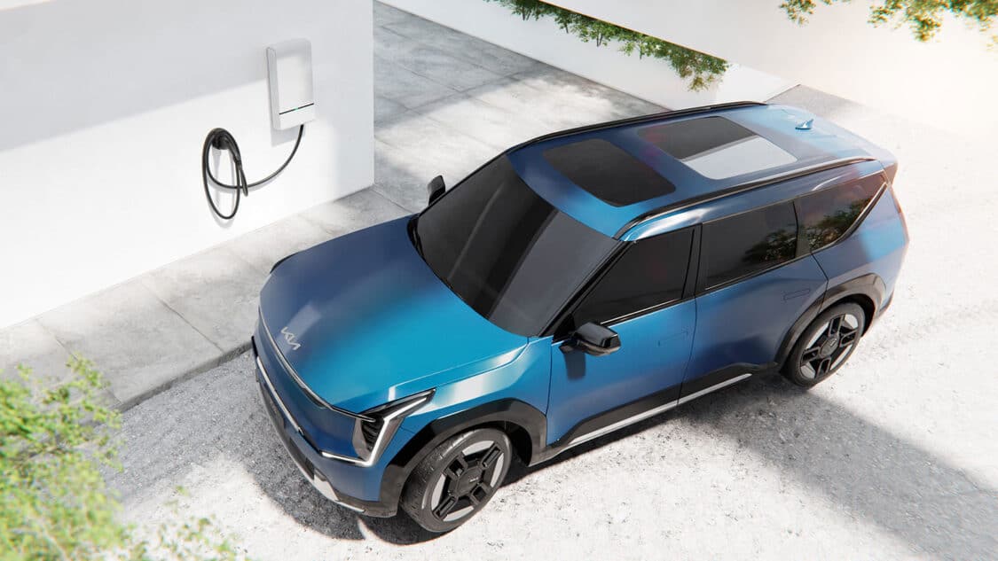 Kia EV9 three-row electric suv view from above next to home charging station