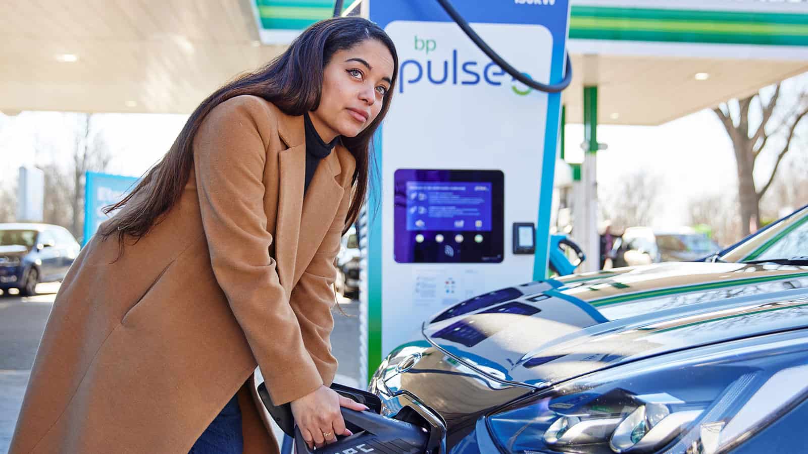 Woman plugging in EV at BP Pulse public charging Gigahub