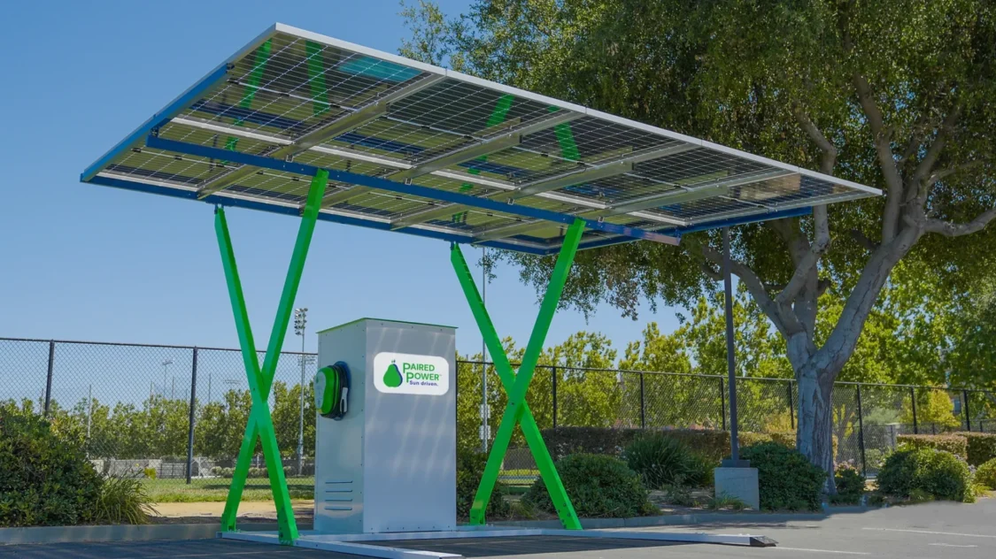 PairTree solar EV charging station, integrated into a microgrid, located in a parking lot with a park behind.