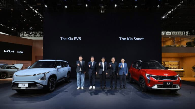 Kia EV5 and Sonet with 5 men standing between them with their thumbs up