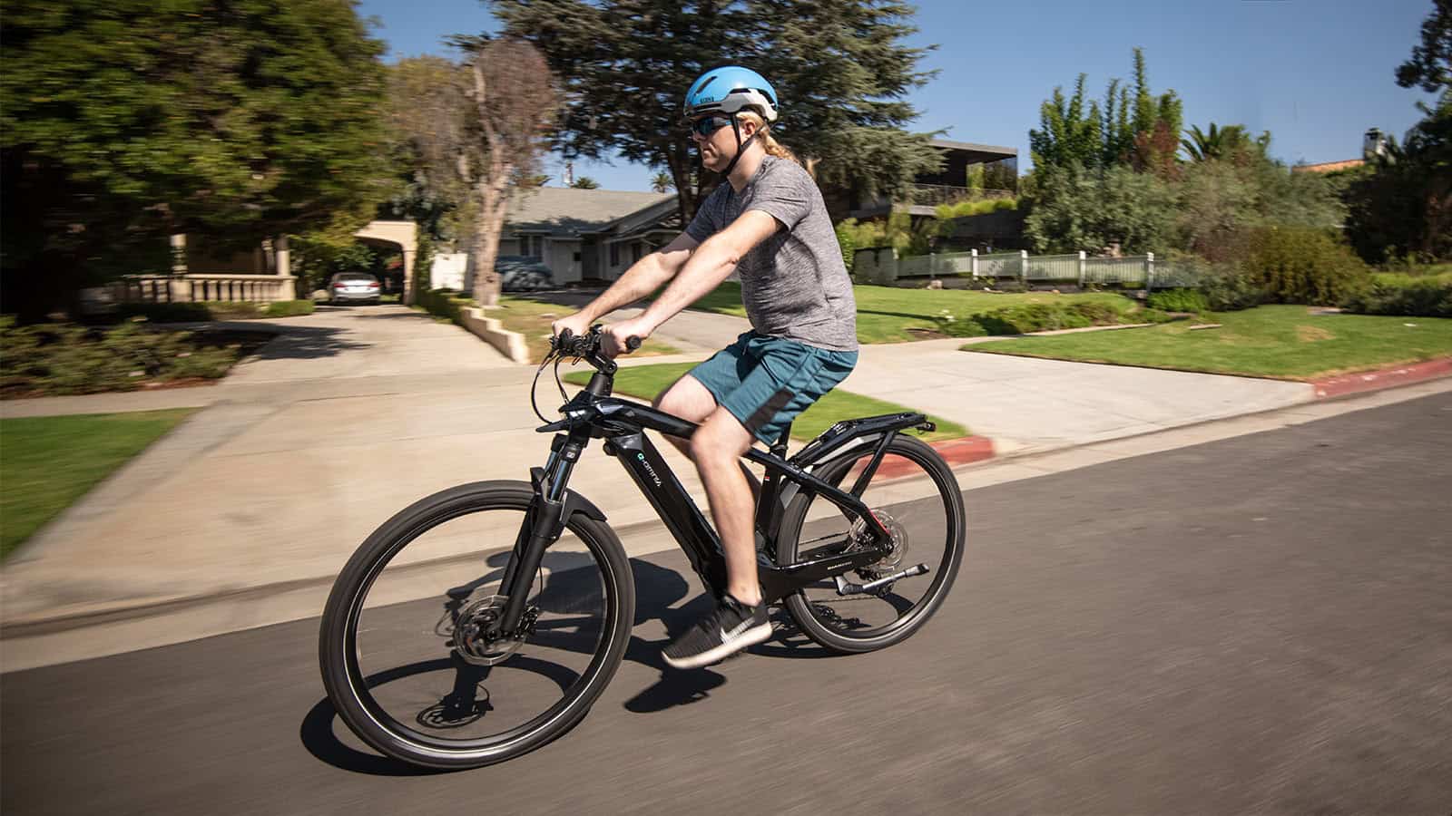 Man riding an electric bike on the road in a residential area rebate e-bike