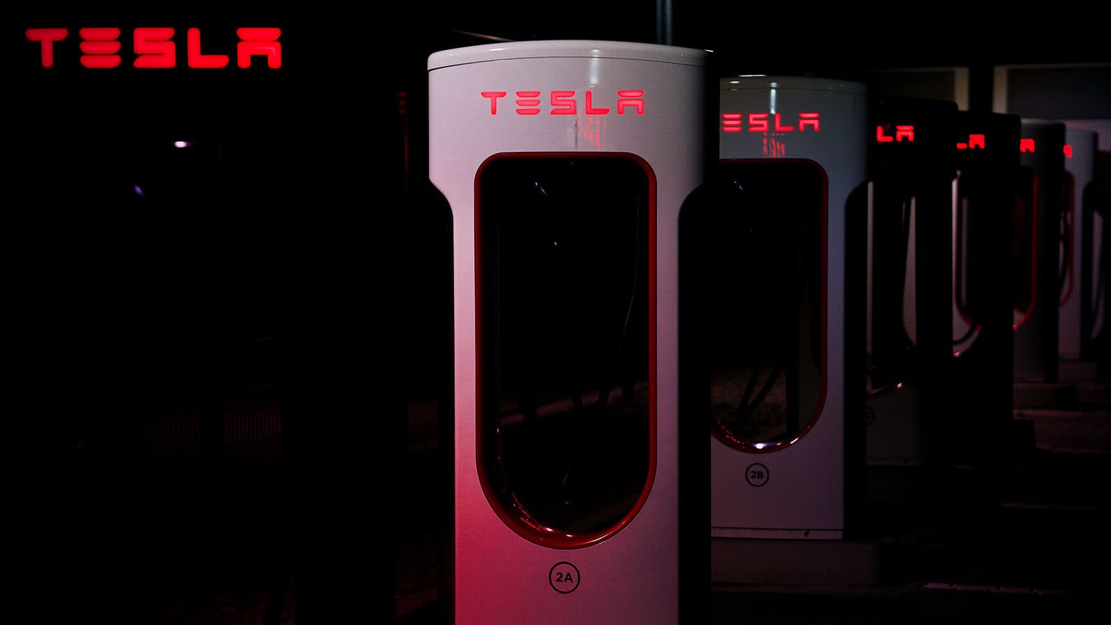 Row of Tesla Superchargers at night with red glow