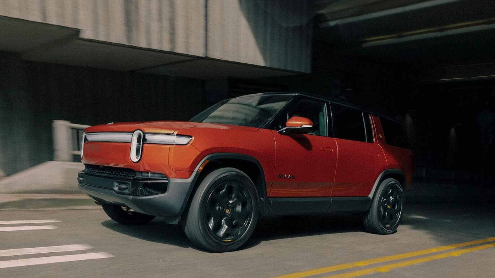 Rivian Tri Max R1S electric SUV in Red Canyon with Darkout accents and 22 inch Sport Wheels.