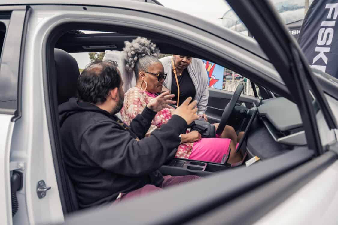 An individual explaining the features of an Ocean electric SUV to two attendees seated inside at Electrify Expo