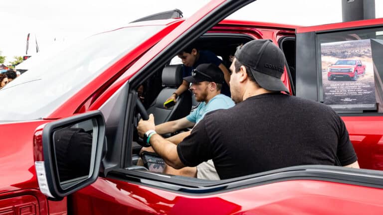 Attendees explore the interior of a red Ford F-150 Lightning electric truck at Electrify Expo.