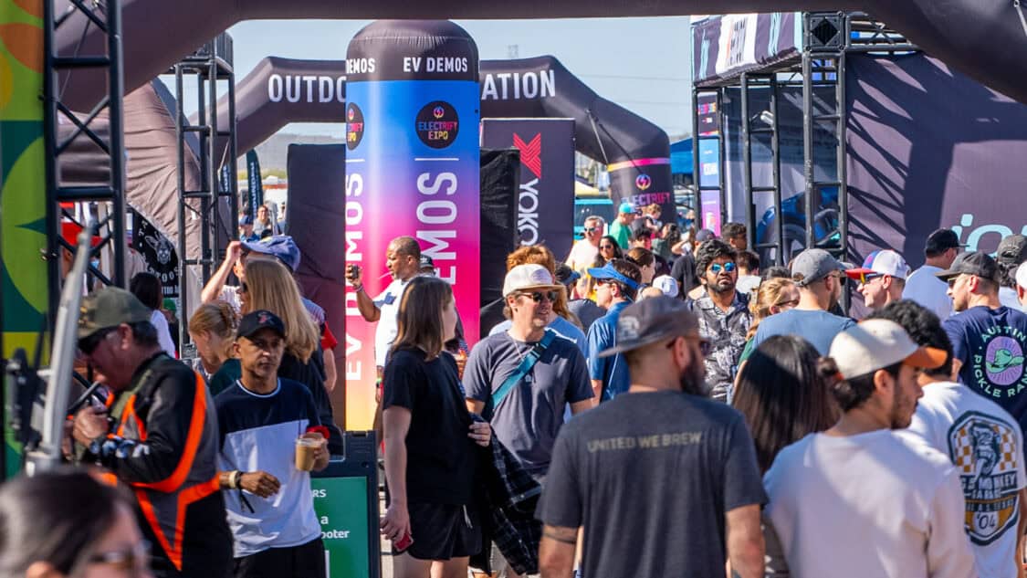 Electrify Expo event with a crowd exploring EV demos and exhibits under branded tents.