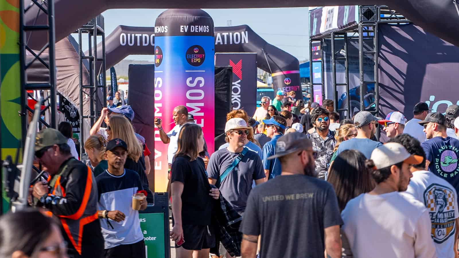 Electrify Expo event with a crowd exploring EV demos and exhibits under branded tents.