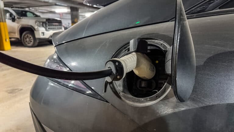 Close-up of a Hyundai Ioniq 6 electric vehicle charging at a home charger in a parking garage.