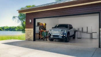 A GMC Sierra EV truck parked in a garage, connected to a bidirectional charging system.