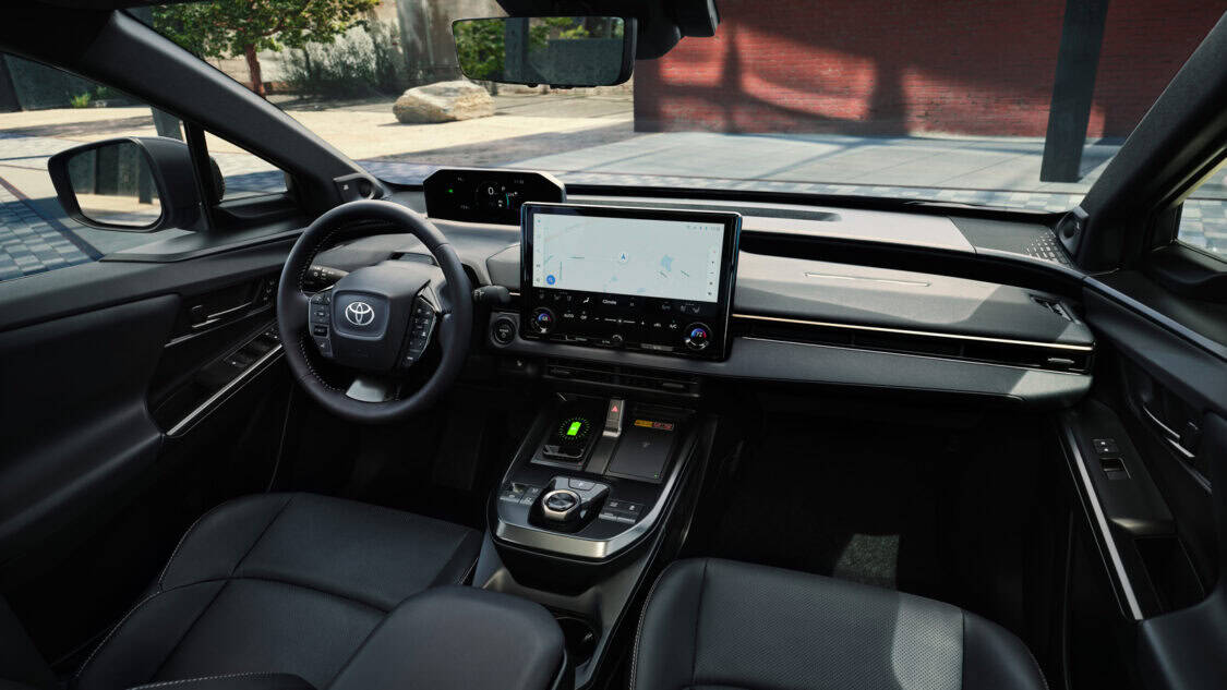 Interior view of the 2026 Toyota bZ electric SUV featuring a large central touchscreen, digital gauge cluster, and modern dashboard design with black leather seats.