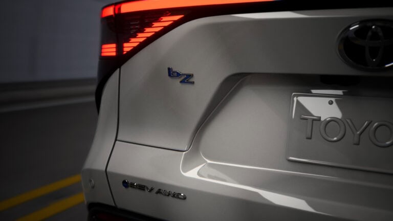 Close-up of the rear of a 2026 Toyota bZ electric SUV, highlighting the bZ and EV AWD badges with illuminated taillights.