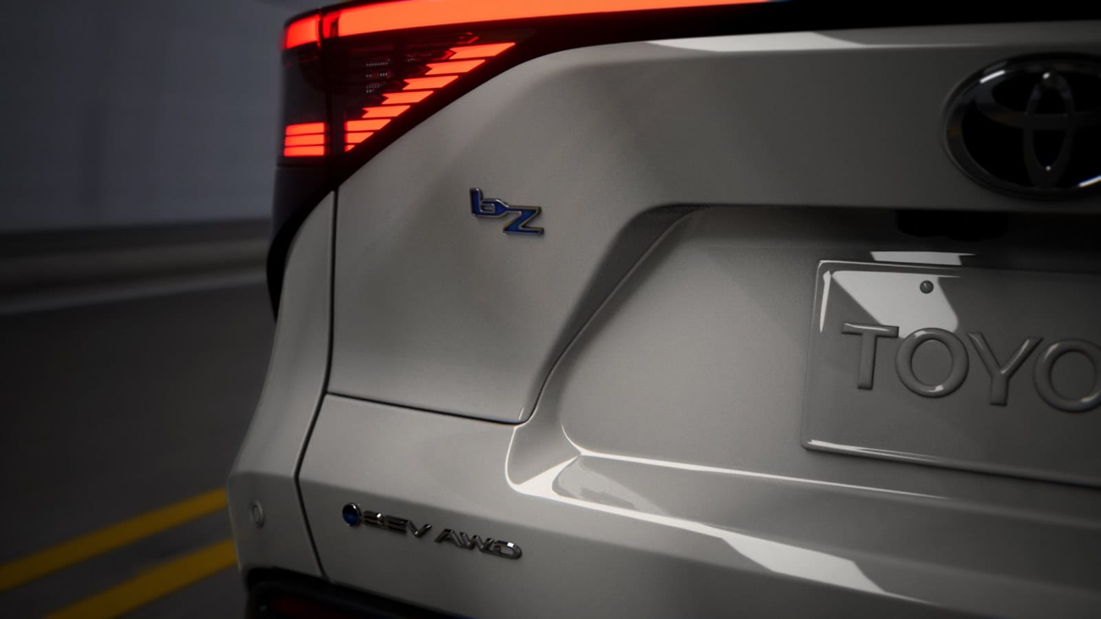 Close-up of the rear of a 2026 Toyota bZ electric SUV, highlighting the bZ and EV AWD badges with illuminated taillights.