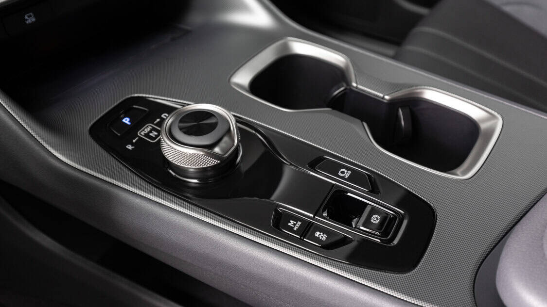 Close-up of the 2026 Lexus RZ 550e center console featuring a rotary gear selector, drive mode buttons, and cup holders.