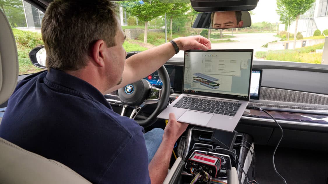 An engineer inside a BMW i7 monitors Solid Power’s all-solid-state battery (ASSB) data on a laptop connected to testing equipment.